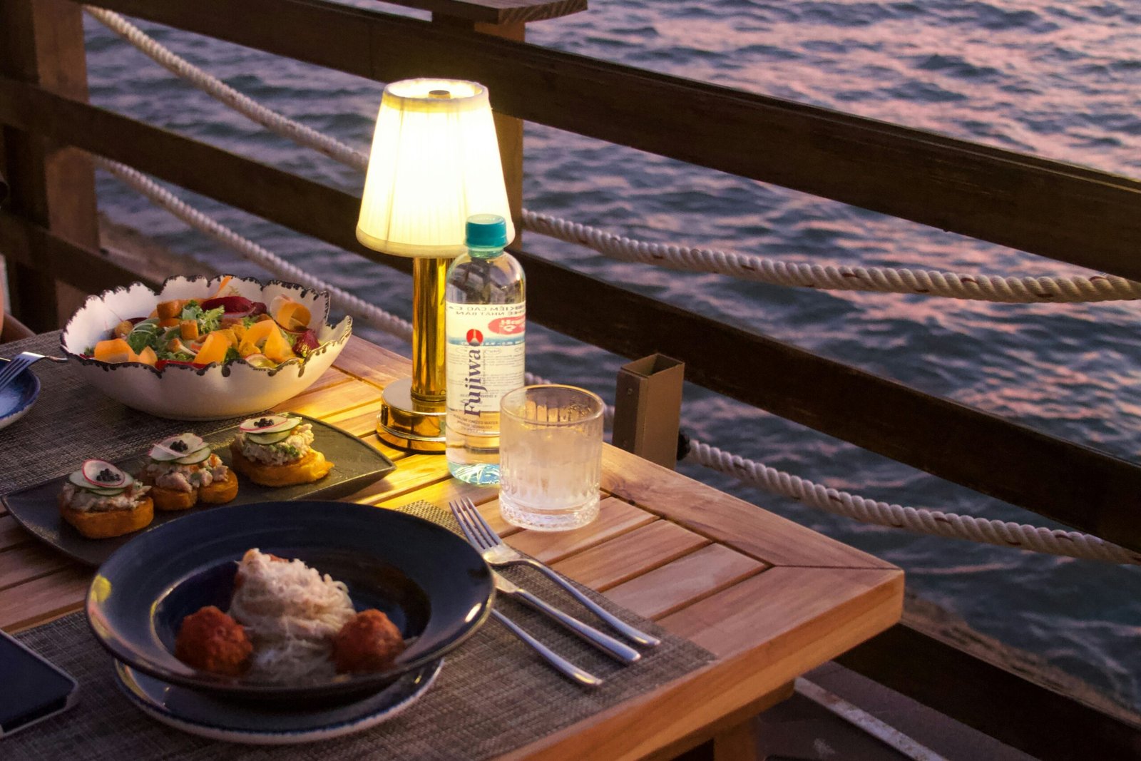 Romantic seaside dinner table set by the water at dusk with ocean views